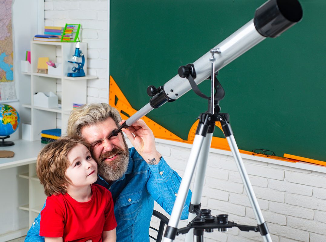 Father and son exploring through a telescope together
